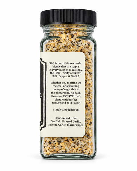 A clear glass spice bottle filled with a beige and brown seasoning blend, featuring a black ribbed cap and a cream-colored label with black text.