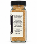 A clear glass spice bottle filled with roasted granulated garlic seasoning, topped with a black cap and featuring a large white product information label on the front.