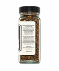A clear glass spice jar with a black screw cap and a cream paper label, filled with black pepper smoked over real applewood. The label features descriptive text in black font.