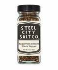 Steel City Salt Co. Applewood Smoked Black Pepper in a clear glass jar with a black lid and cream label, shown on a white background.